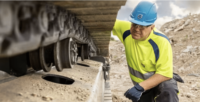 Technician inspecting a Volvo excavator undercarriage