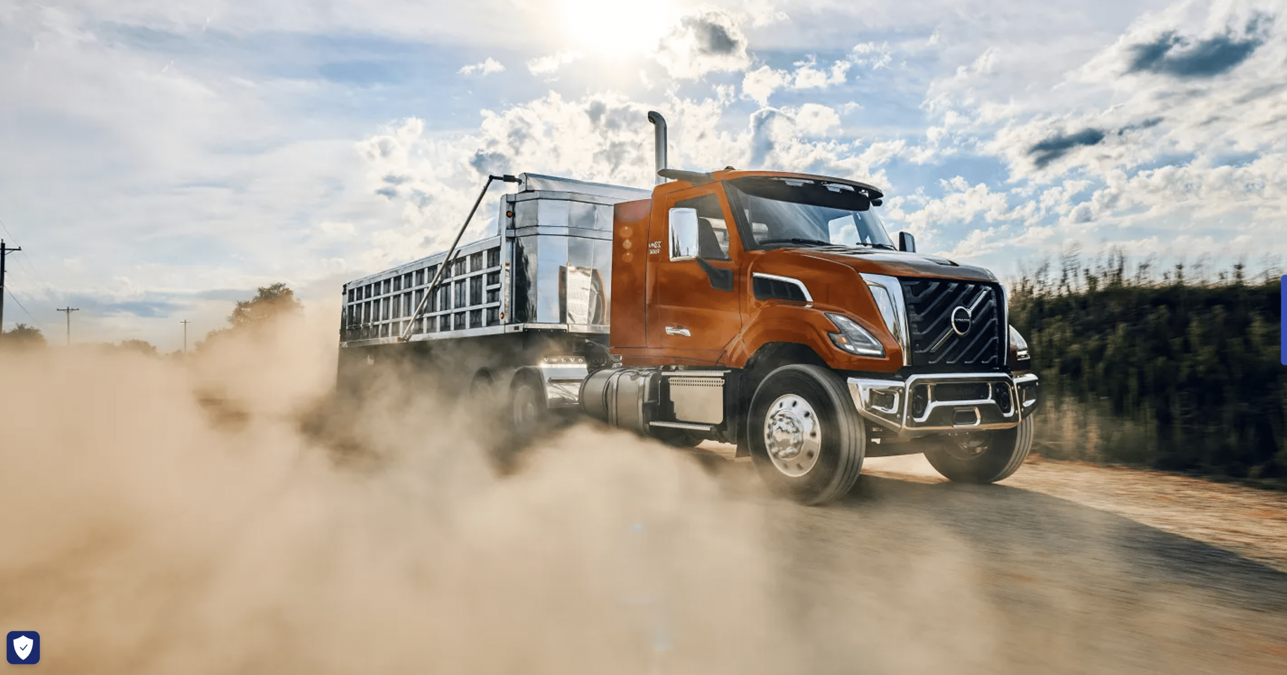 Orange all-new Volvo VNX 300 daycab pulling an aluminum end-dump trailer down a dusty gravel road