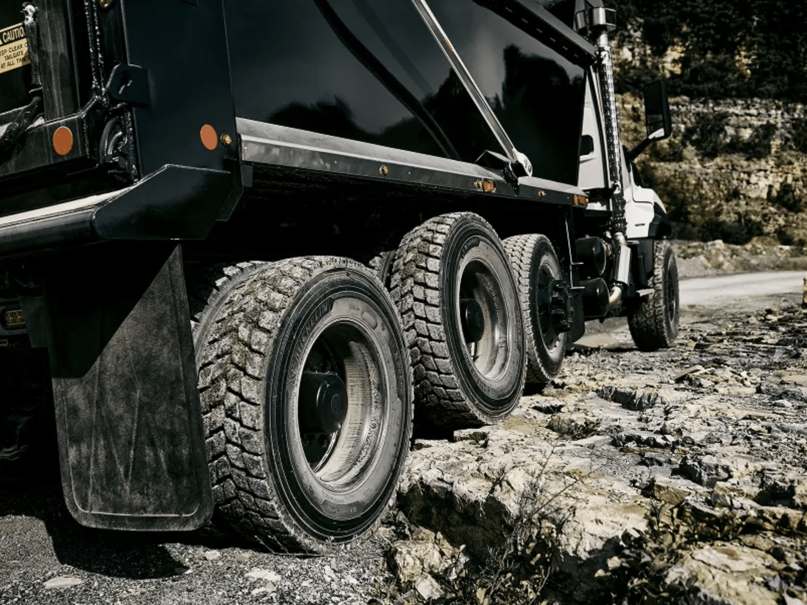 White VNX dump truck driving toward the camera through quarry dust